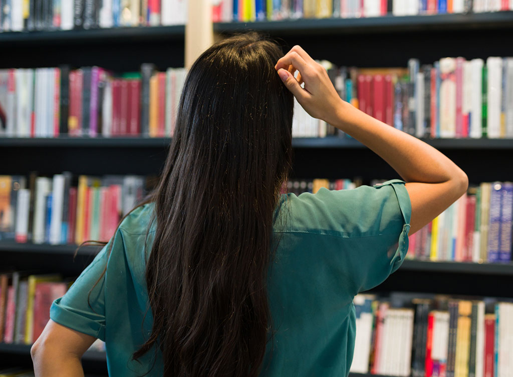 Young lady looking at row of books in library